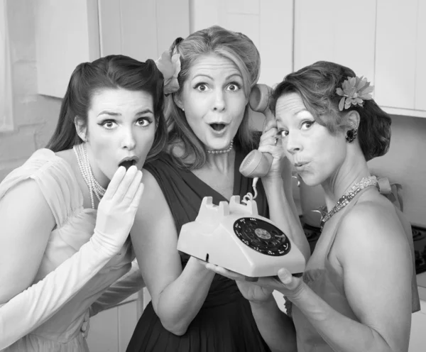 Tres mujeres retro sorprendidas con un teléfono antiguo